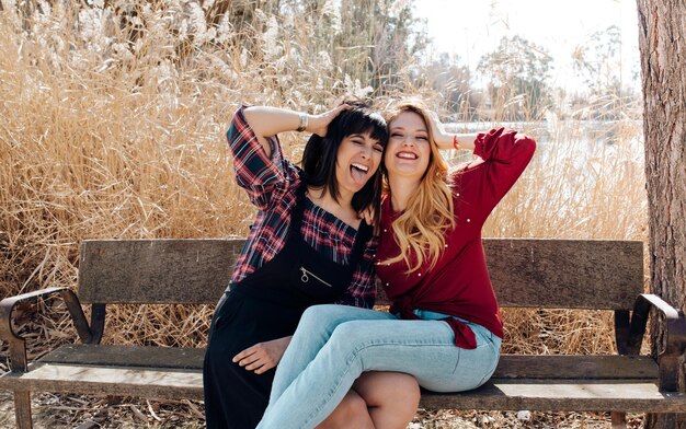 Photo young women sitting on bench and looking at camera