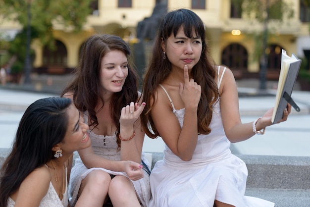 Young women sitting on smart phone outdoors