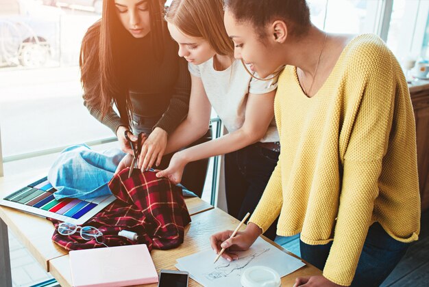 Foto giovani donne che stanno insieme e lavorano per lo stesso progetto di moda