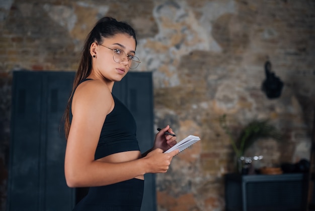 Young women standing writing down something into the notebook