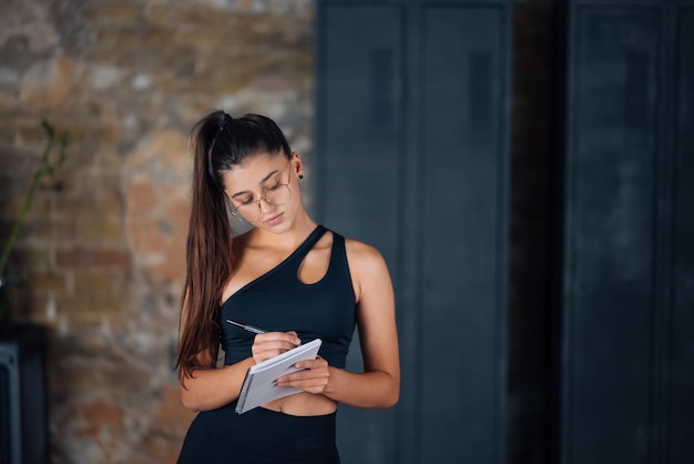 Young women standing writing down something into the notebook