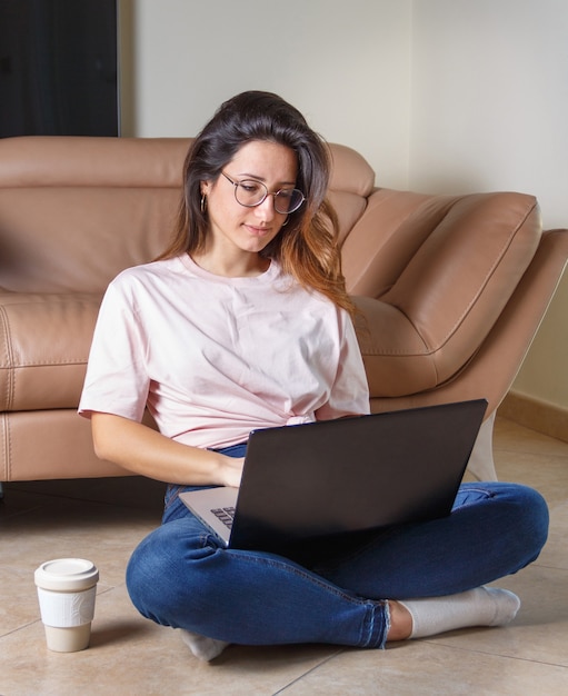 Молодые женщины с ноутбуком, сидя на полу дома