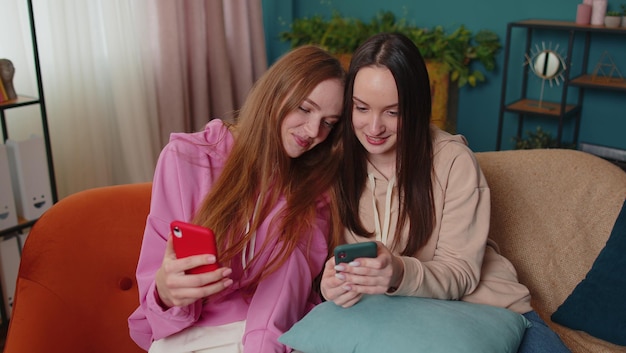 young women using mobile phone while sitting on sofa at home