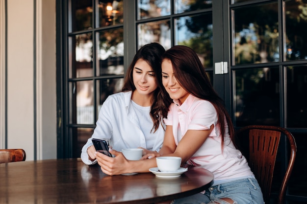 Молодые женщины смотрят в смартфон в кафе