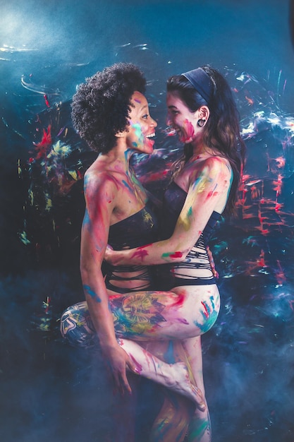 Foto giovani donne che indossano un bikini mentre sono ricoperte di vernice per il corpo in un nightclub