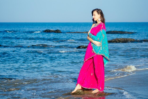 Young women wearing a pink blue saree on the beach goa Indiagirl in traditional indian sari on the shore of a paradise island among the rocks and sand enjoying the freedom and the morning