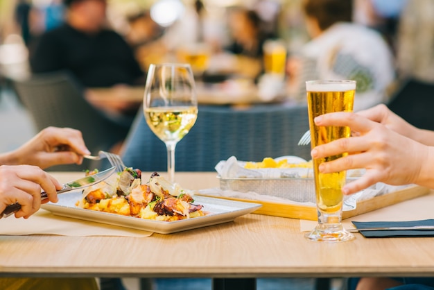 Foto giovani donne con birra e vino e mangiare cibo sulla terrazza - due ragazze pranzano insieme in un ristorante