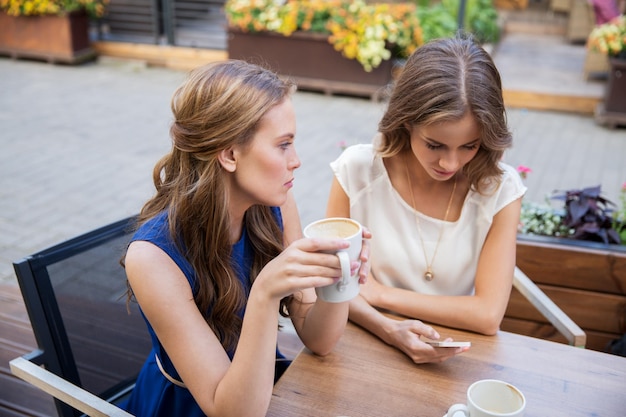 young women with smartphone and coffee at cafe