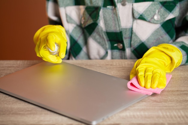 Young worker cleaning table with rag in office.