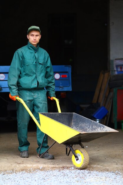 A young worker holds a wheelbarrow