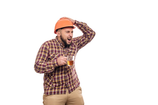 Photo young worker in an orange helmet holds a cup of tea, isolated white background