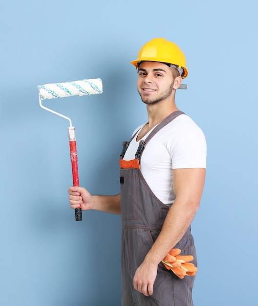 Young worker renewing apartment on wall background