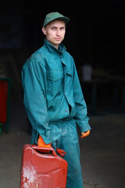 A young worker in uniform holds a canister of gasoline