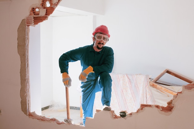 Photo young worker with a red protection helmet and wearing a blue boiler suit. demolition concept