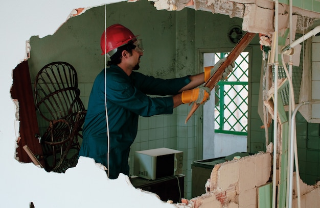 Photo young worker with a red protection helmet and wearing a blue boiler suit. demolition concept