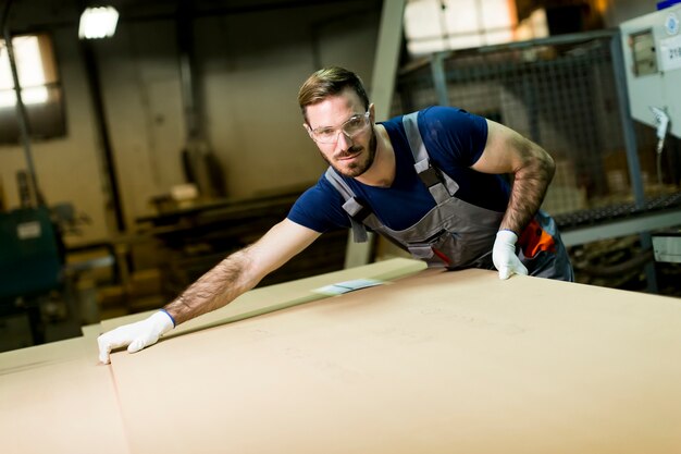 Young worker works in a factory for the production of furniture