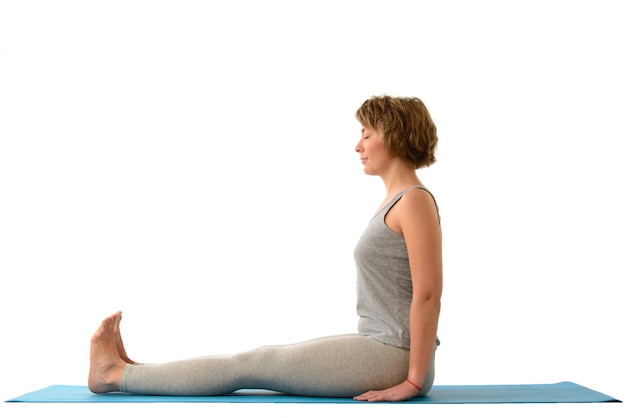 Young yoga woman in the paschimottanasana position. Isolated on white wall 