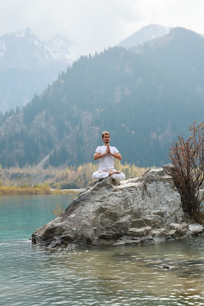 Молодой человек дзэн в медитации. Йога на открытом воздухе в горном озере. Упражнение Агни Стамбхасана.