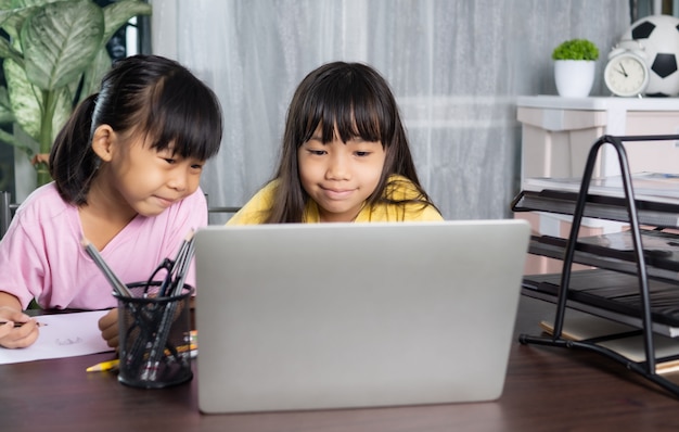 Younger and older sister study and learning online at home, education and knowledge concept