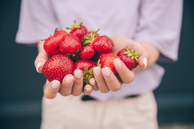 YounWoman's hands holding red strawberries and cherries