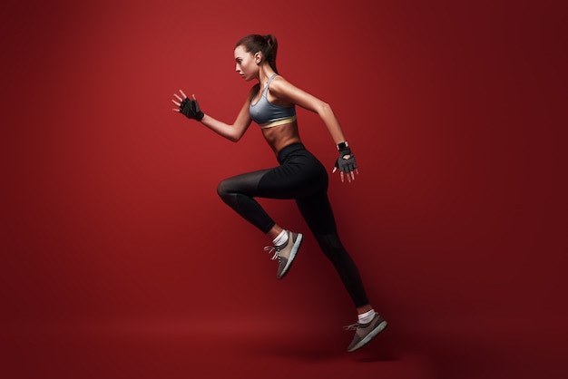 Do your best sportswoman jumping over red background isolated