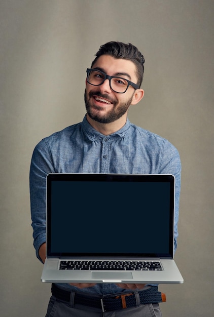 Foto il tuo sito web aziendale starebbe benissimo qui ritratto in studio di un giovane in possesso di un laptop su uno sfondo grigio