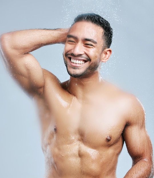 Your mood always lightens after a shower Studio shot of a handsome young man taking a shower against a grey background