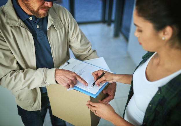 Your signature here pleas maam Shot of a young woman signing for a package from a delivery man