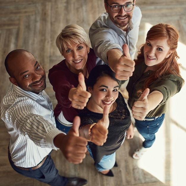 Your success is reaching new heights. High angle portrait of a team of colleagues giving a thumbs up in a modern office.