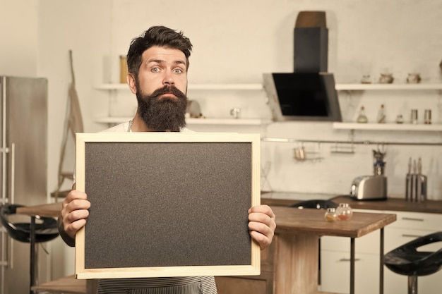 Your text here brutal hipster man holding blank board copy space job search there are vacancies shopping sale and discounts chef menu in kitchen look over there chalkboard for advertising