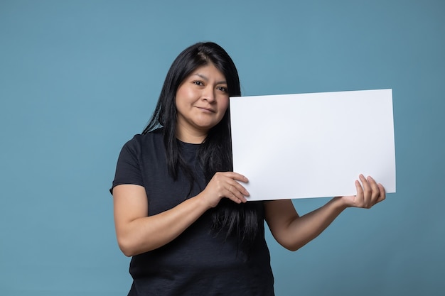 Your text here. Mexican Latin woman holding empty blank board. Studio portrait with blue background.