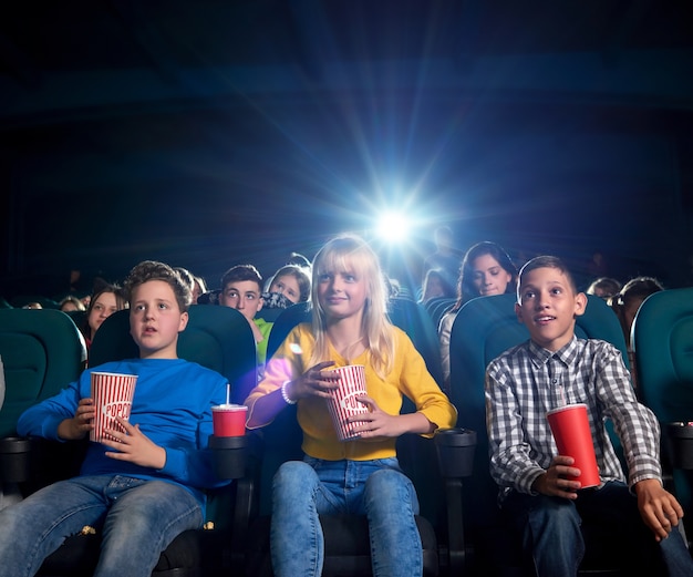 Giovani che guardano film e mangiano spuntini nel cinema.