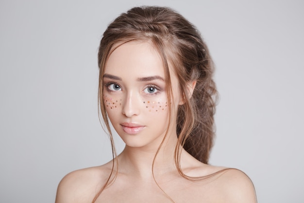 Youth women with glitter freckles on the face, beautiful hairstyle