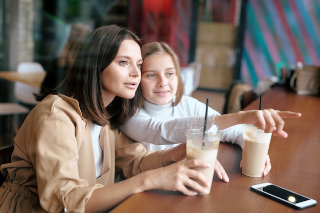 youthful girl pointing forwards while showing her mom something curious