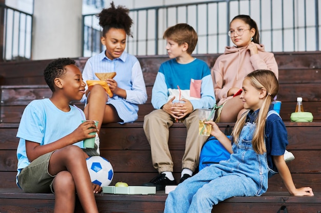 Photo youthful intercultural school friends with soda looking at one another