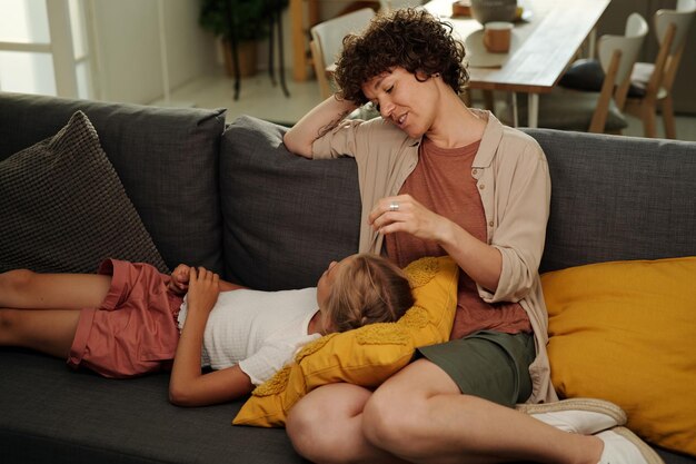 Youthful serene girl lying on pillow on her mother knees and having chat