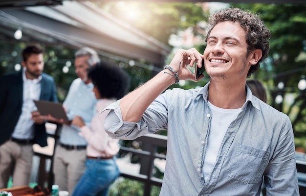 Youve given me the best news ever Shot of a businessman talking on a cellphone outside with his colleagues in the background