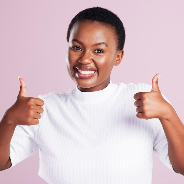 Youve got this Studio portrait of a young woman showing two thumbs up against a pink background