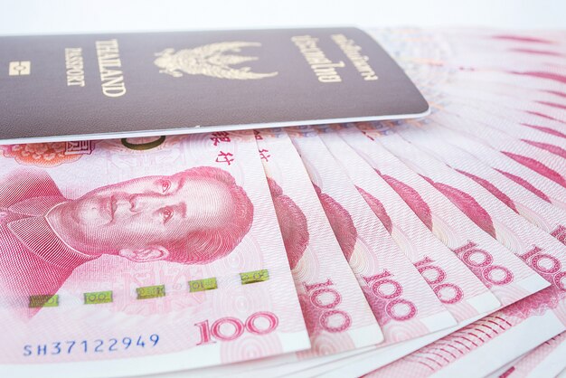 旅の準備ができている中国の通貨とタイの旅券からの元の銀行券