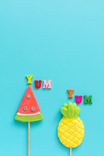 Yum Yum, pineapple and watermelon lollipopson blue yellow background. Concept vacation or holidays