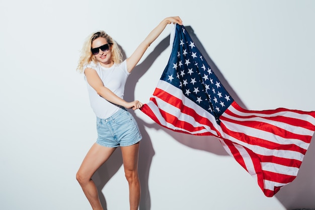 Photo yung caucasian blonde woman in sunglasses posing and waving usa flag, independence day celebration