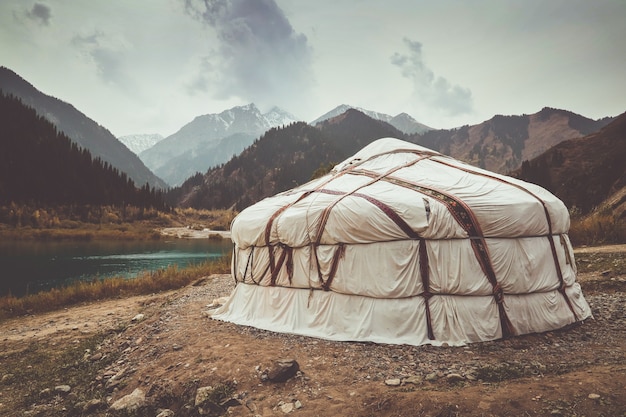 Yurt on the lake in the mountains of Kazakhstan. Snowy mountain peaks.