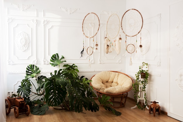 Zaal binnenland met tropische houseplantsmonstera, dreamcatchers en papasan stoel