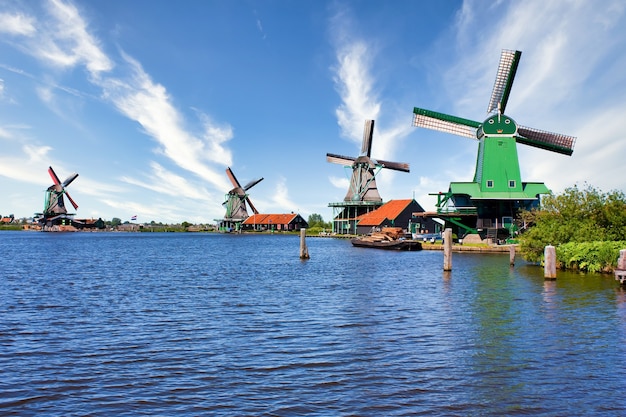 ZAANSE SCHANS, NETHERLANDS - 2020년 8월경: 푸른 하늘과 강물이 있는 암스테르담에 가까운 녹색 시골에 있는 네덜란드 풍차.