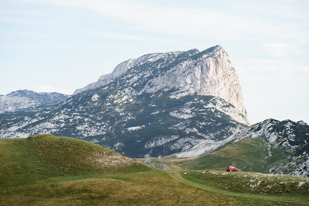 Zabljak montenegro juli toeristen in een rode auto kampeerden op het gras tegen de achtergrond van een rocky