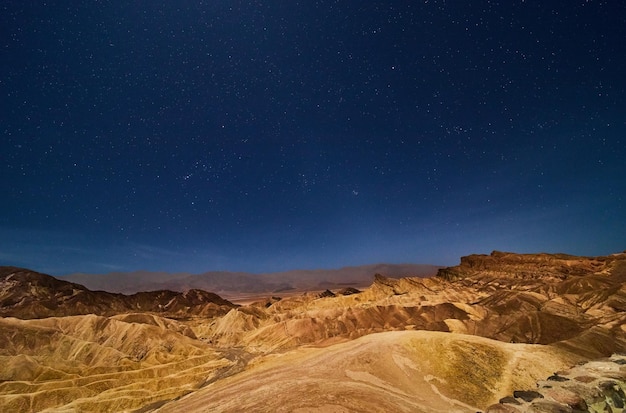 Zabriskie Point in Death Valley starry night with colorful waves in desert mountains