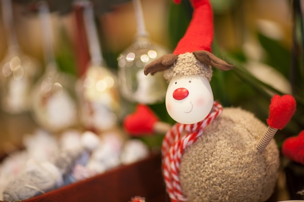 Zacht speelgoed kerstrendier met een rode sjaal en een hoed op een onscherpe achtergrond