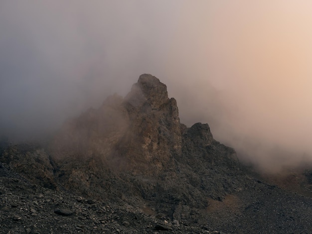 Zachte focus. Dramatische mist tussen gigantische rotsachtige bergen. Spookachtig sfeervol uitzicht op grote klif in bewolkte hemel. Lage wolken en prachtige rotspartijen. Minimalistische landschap mysterieuze plek.