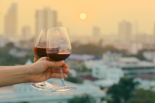 Zachte focus op rode wijnglazen vrouwen met rode wijnglazen op balkon tijdens zonsondergang