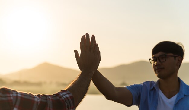 Zachte focus van de hand van twee man die tijdens zonsondergang een vuist voor de berg geeft